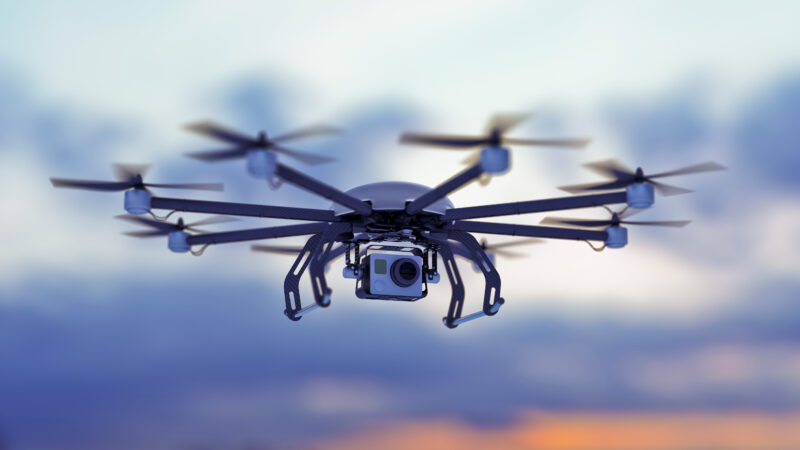 a drone flying in a cloudy sky where the sun goes down